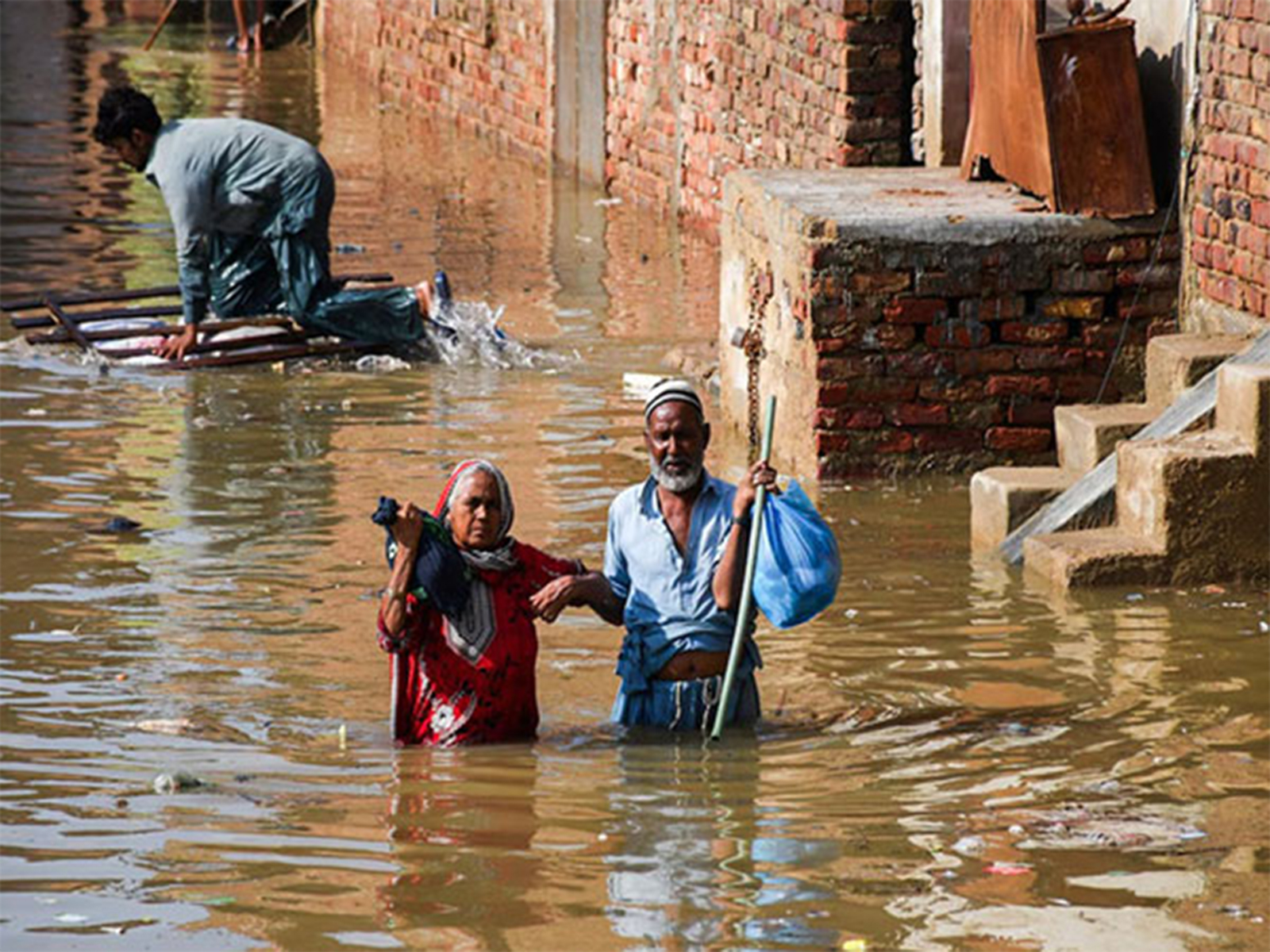 Flood-hit residents carry belongings through inundated streets in Karachi (File Photo/Reuters)