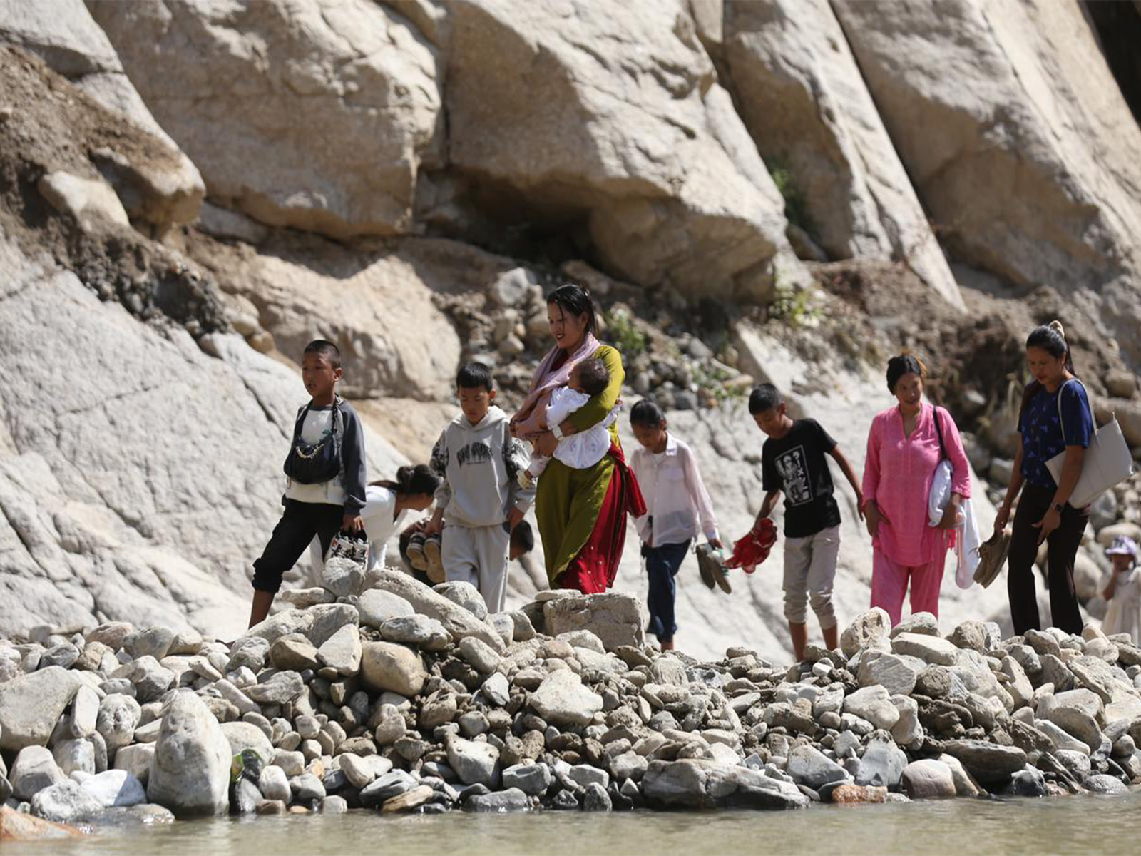 People, including women and children, cross a damaged section of the BP Highway in Nepal by wading through the Roshi River after heavy rains washed away road diversions, disrupting travel across the region. (Photo/ANI) People, including women and children, cross a damaged section of the BP Highway in Nepal by wading through the Roshi River after heavy rains washed away road diversions, disrupting travel across the region. (Photo/ANI)