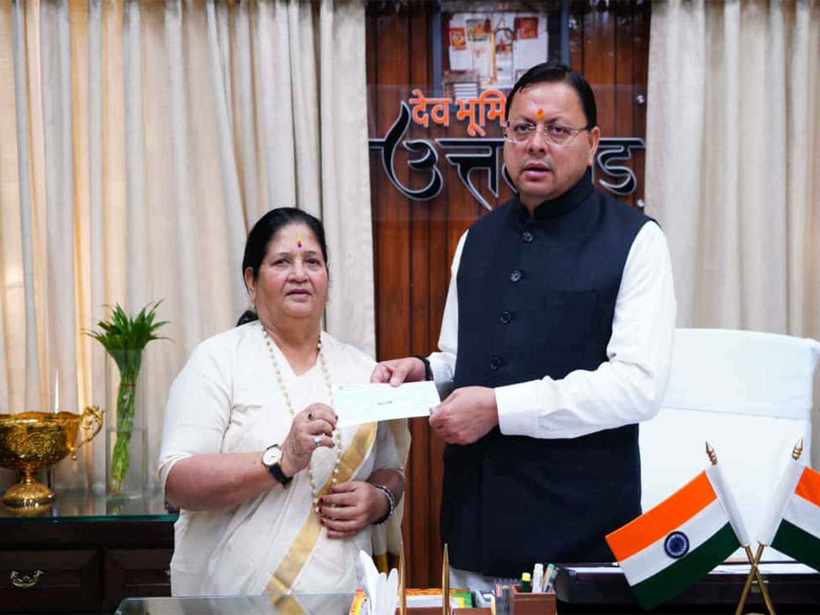 On Bachendri Pal's behalf Vice Chairperson of State Women’s Entrepreneurship Council Vinod Uniyal handed over ₹10 lakh cheque to CM Dhami (Photo/ANI)
