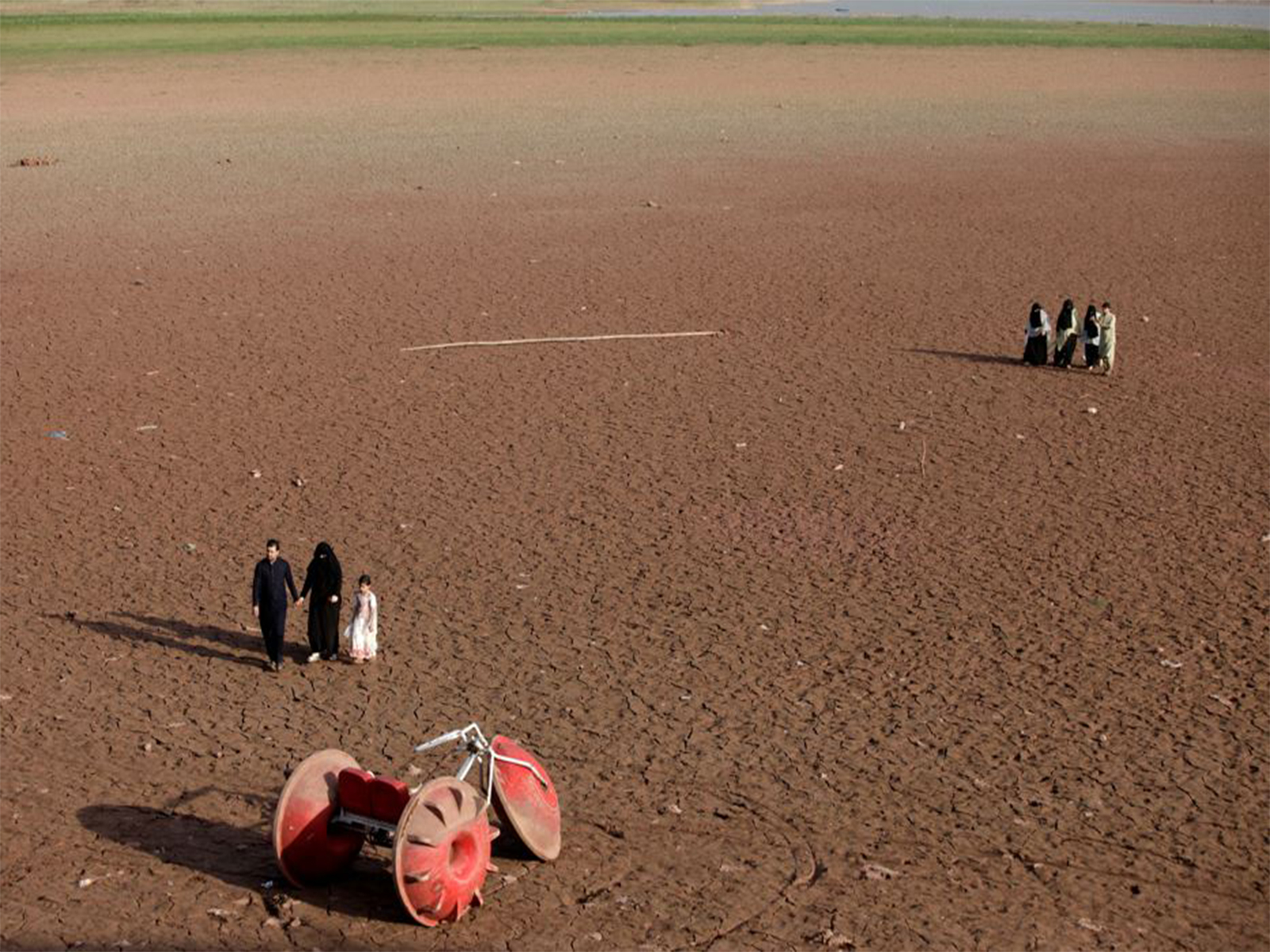 People walk near a three-wheeler parked at a dry portion of land that used to have water in Pakistan (File Photo/ Reuters) People walk near a three-wheeler parked at a dry portion of land that used to have water in Pakistan (File Photo/ Reuters)