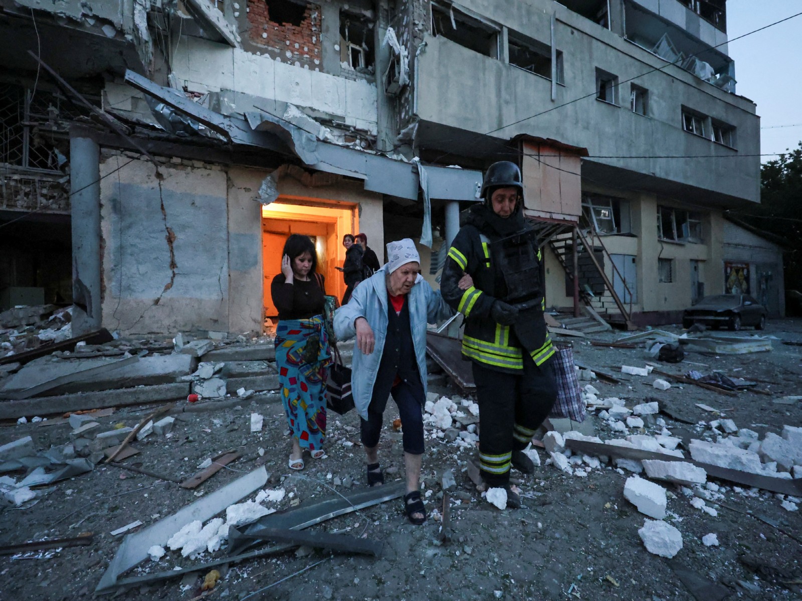 A rescuer helps a woman evacuate an apartment building damaged in a Russian drone strike in Kharkiv, Ukraine. (File Photo/Reuters)