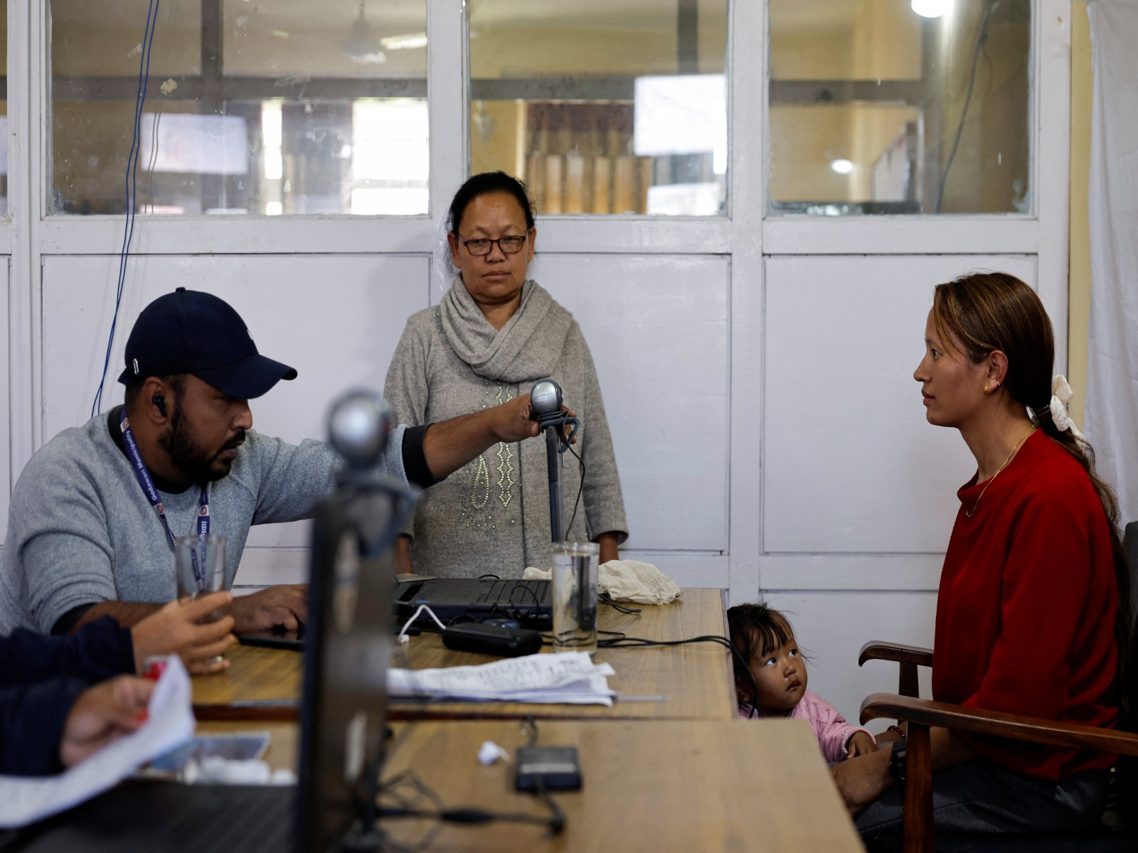 A girl looks towards her mother as she waits to give her biometric information to register on the voters' list for the upcoming House of Representatives elections scheduled for March 5, 2026 (Photo/Reuters)