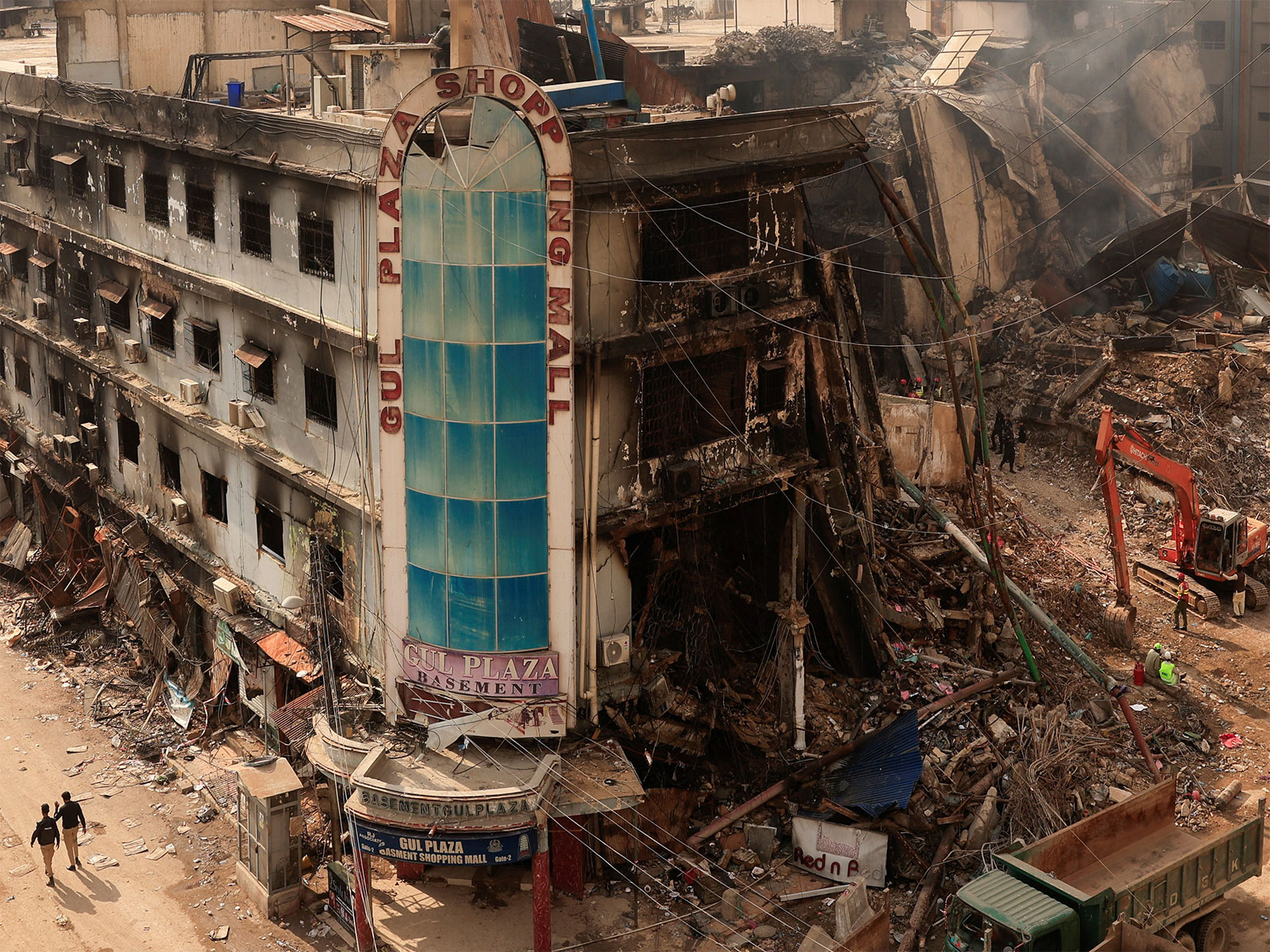 Police personnel walk past the gutted Gul Plaza Shopping Mall following a massive fire in Karachi. (Photo/Reuters)