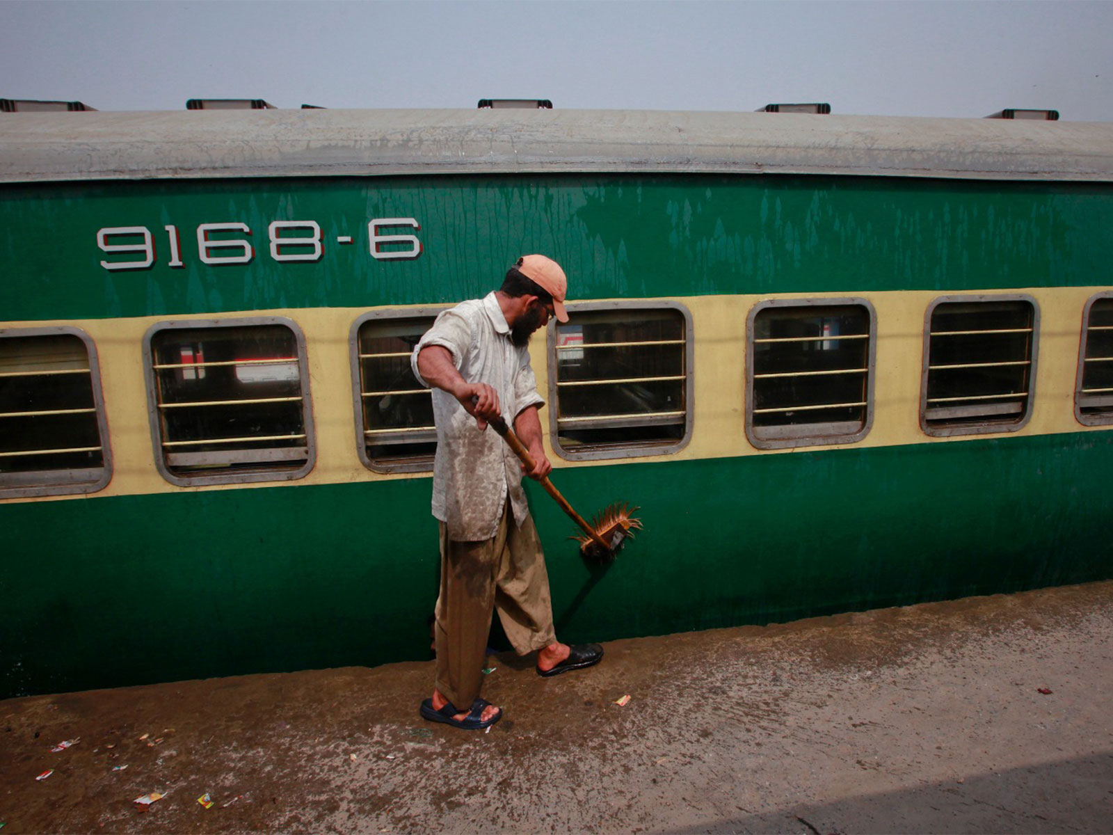 A man washes a passenger train carriage parked in a railway station yard in Lahore (File Photo/Reuters) 