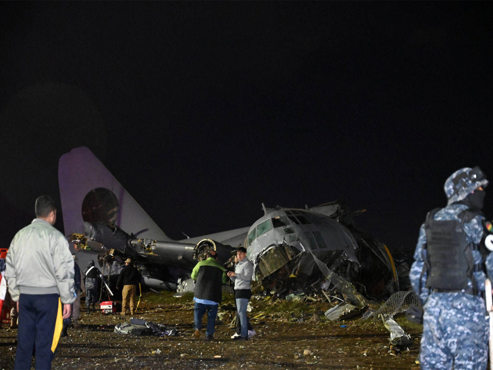 People stand at the site where a Bolivian Air Force Hercules aircraft crashed on Friday evening (Photo/Reuters)
