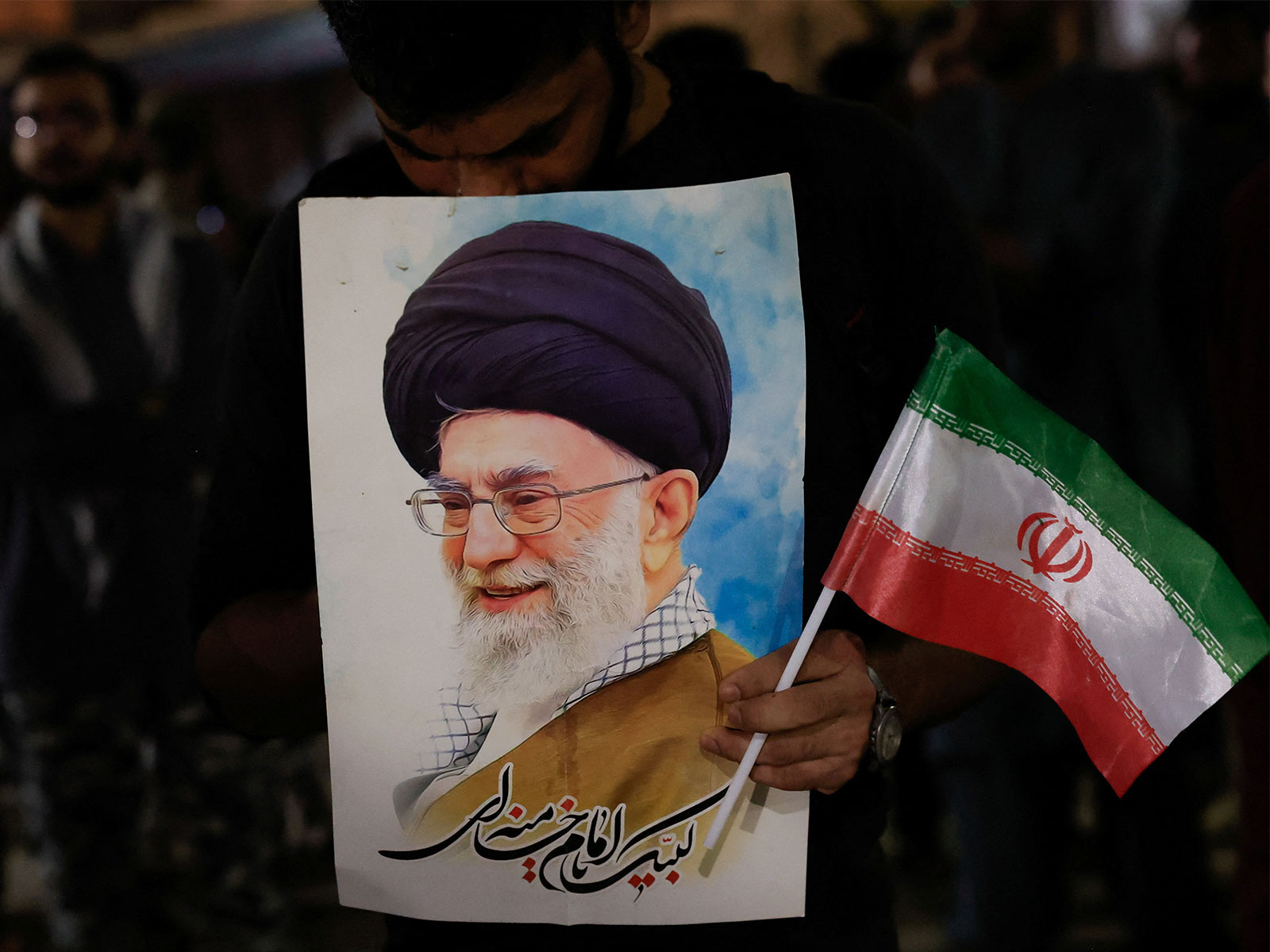 A mourner holds a portrait of Iran's Supreme Leader Ayatollah Ali Khamenei along with an Iranian flag during a gathering following reports of his killing. (Photo/Reuters)