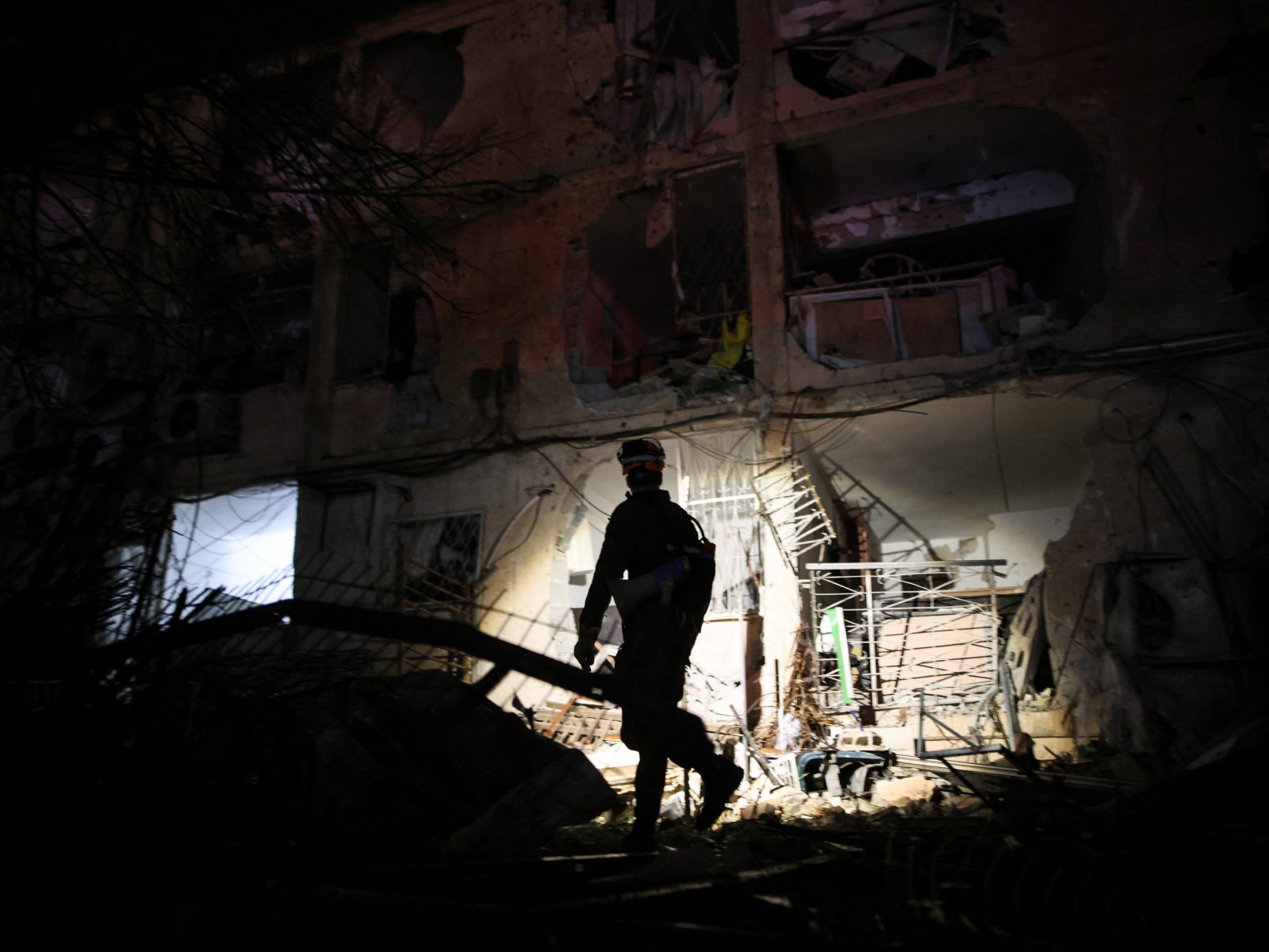 An Israeli emergency response official uses a torch to inspect the damage after Iranian missile barrages struck Dimona, amid the US-Israel conflict with Iran, in southern Israel (Photo/Reuters)