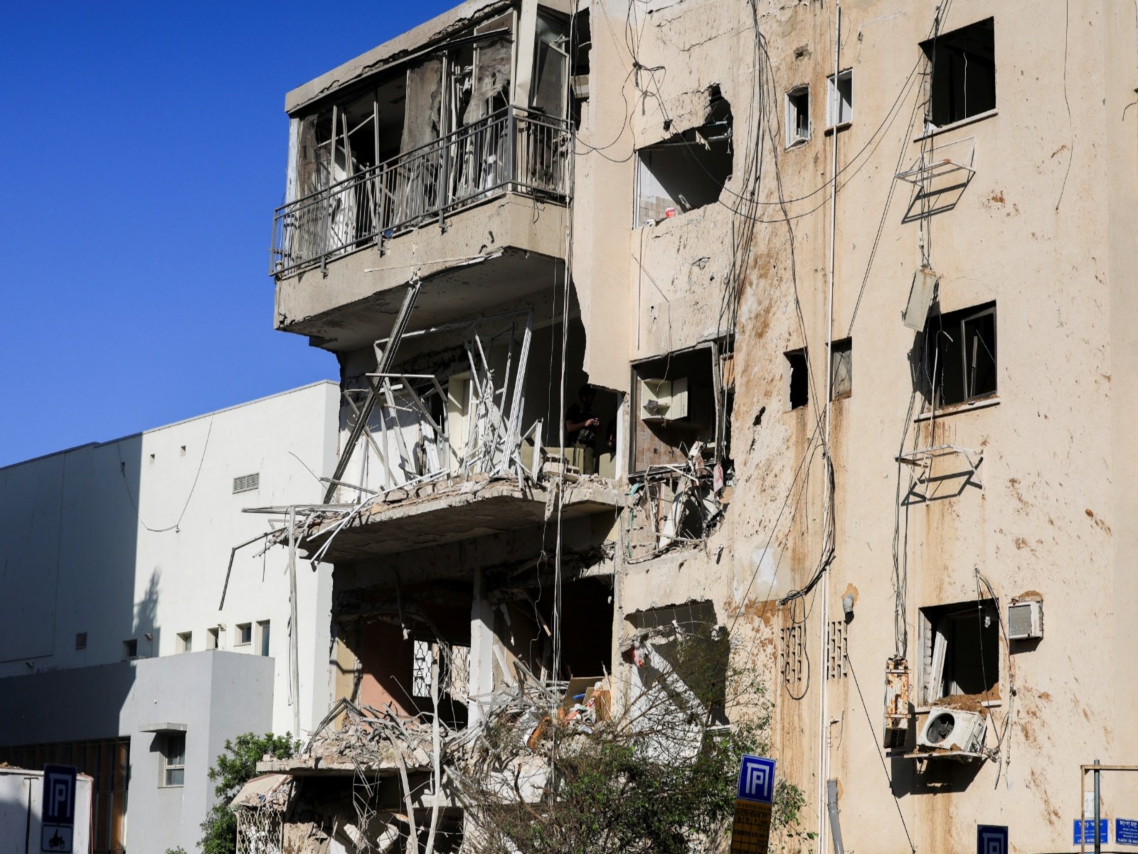 Debris hangs from a damaged building at the site following Iranian missile barrages in central Israel (Photo/ Reuters)