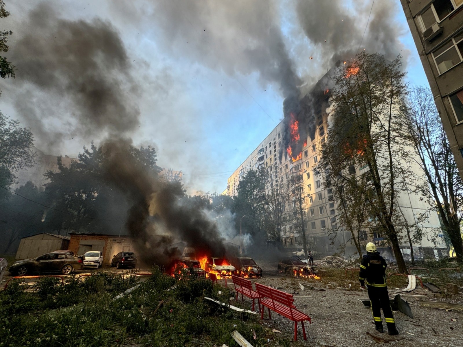 A firefighter looks at an apartment building and cars which burn after a Russian air strike (REUTERS/ANI Photo)