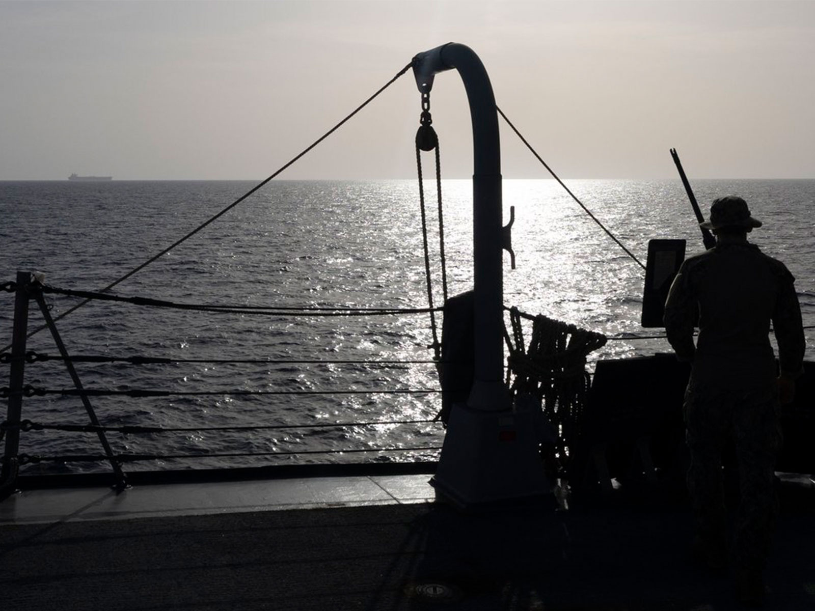A US Sailor watches a commercial vessel as American forces continue to enforce a blockade against Iranian ports. (Photo: X/@CENTCOM)