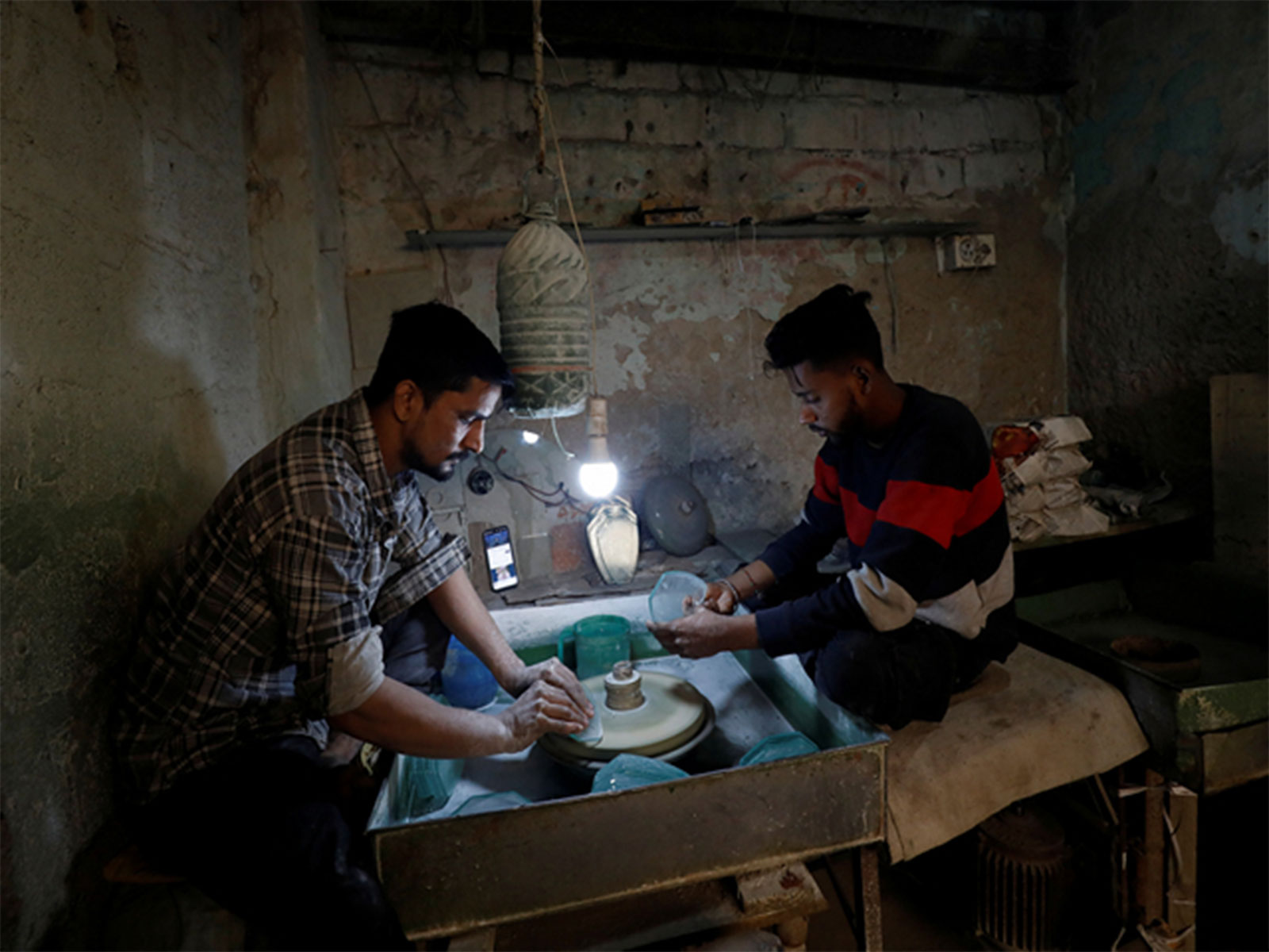 Workers shape glass pieces on a machine in a workshop, a day after a country-wide power breakdown in Karachi (File Photo/ Reuters)