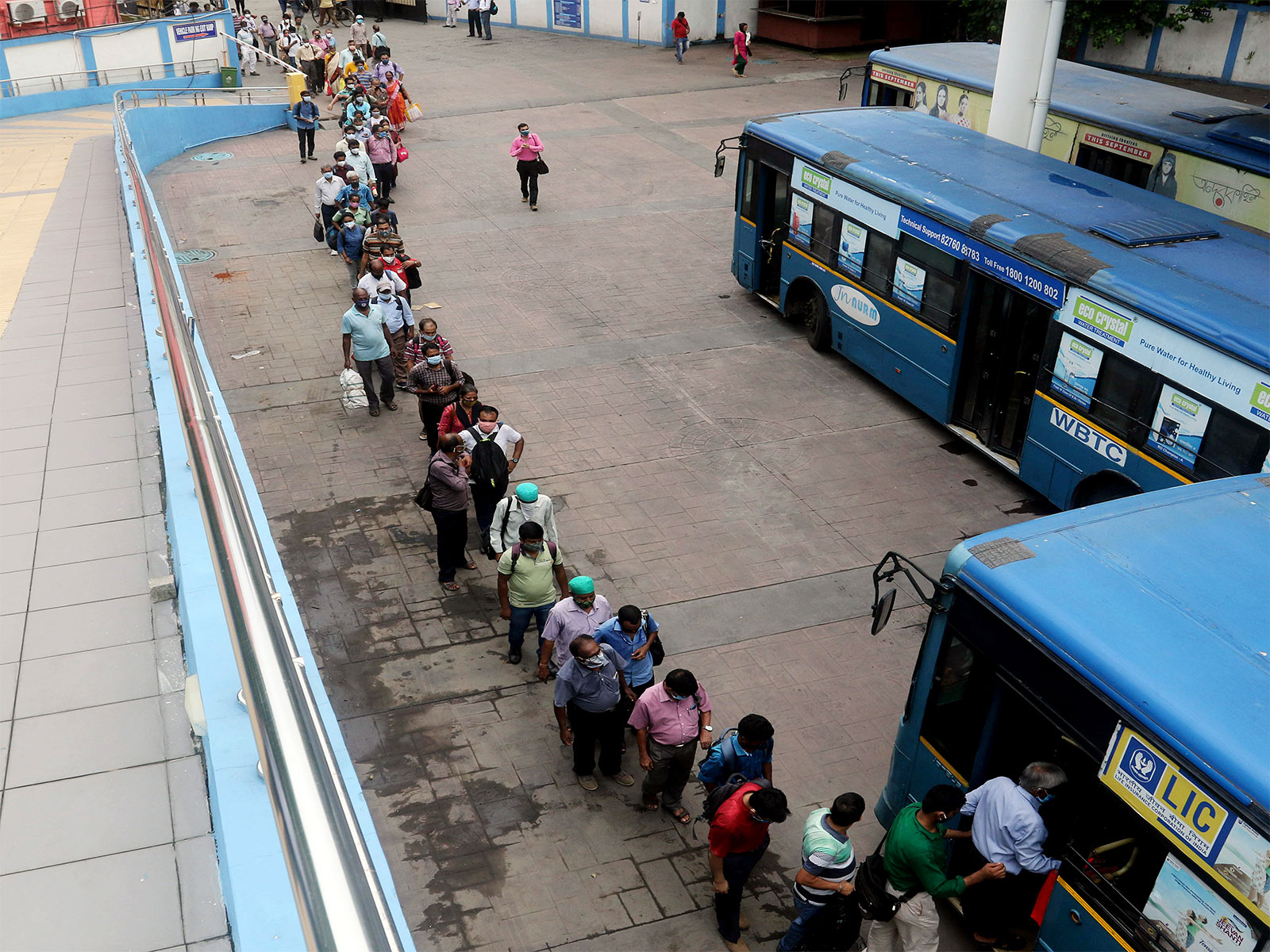 Commuters stand in a queue to board a bus as WBTC (Photo/ANI)