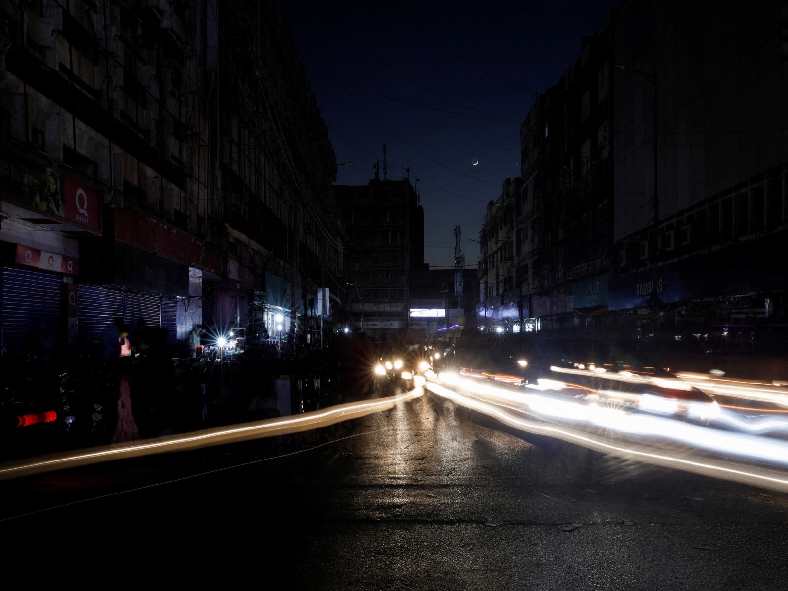 Vehicle headlights create light trails along a market road during a widespread power outage in Pakistan. (Photo/Reuters) Vehicle headlights create light trails along a market road during a widespread power outage in Pakistan. (Photo/Reuters)
