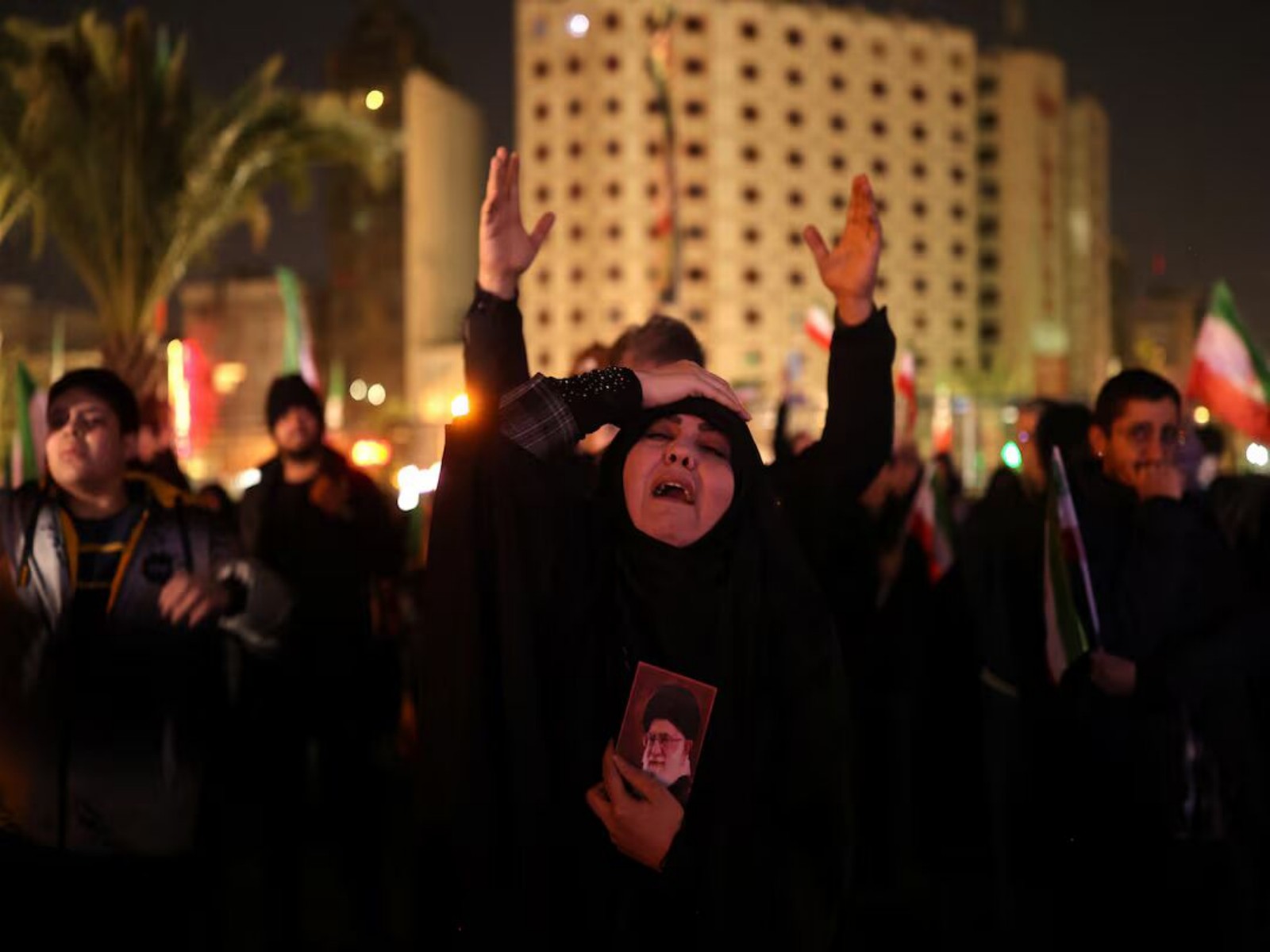 Mourners gather in Tehran as a woman holds a portrait of late Supreme Leader Ayatollah Ali Khamenei. (Photo/Reuters)