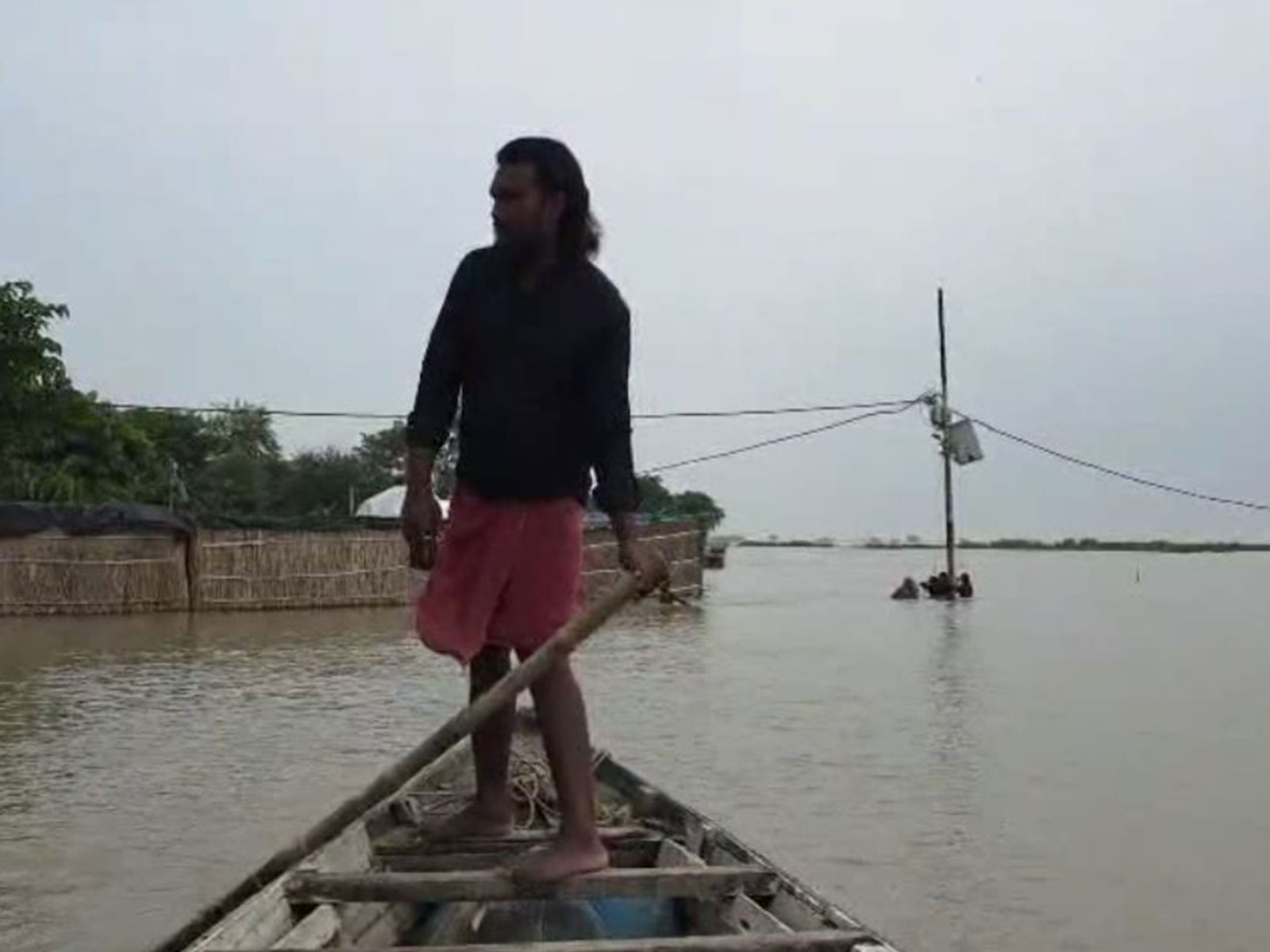 A man navigates a small boat through a flooded area near submerged houses and power lines (Photo/ANI) A man navigates a small boat through a flooded area near submerged houses and power lines (Photo/ANI)