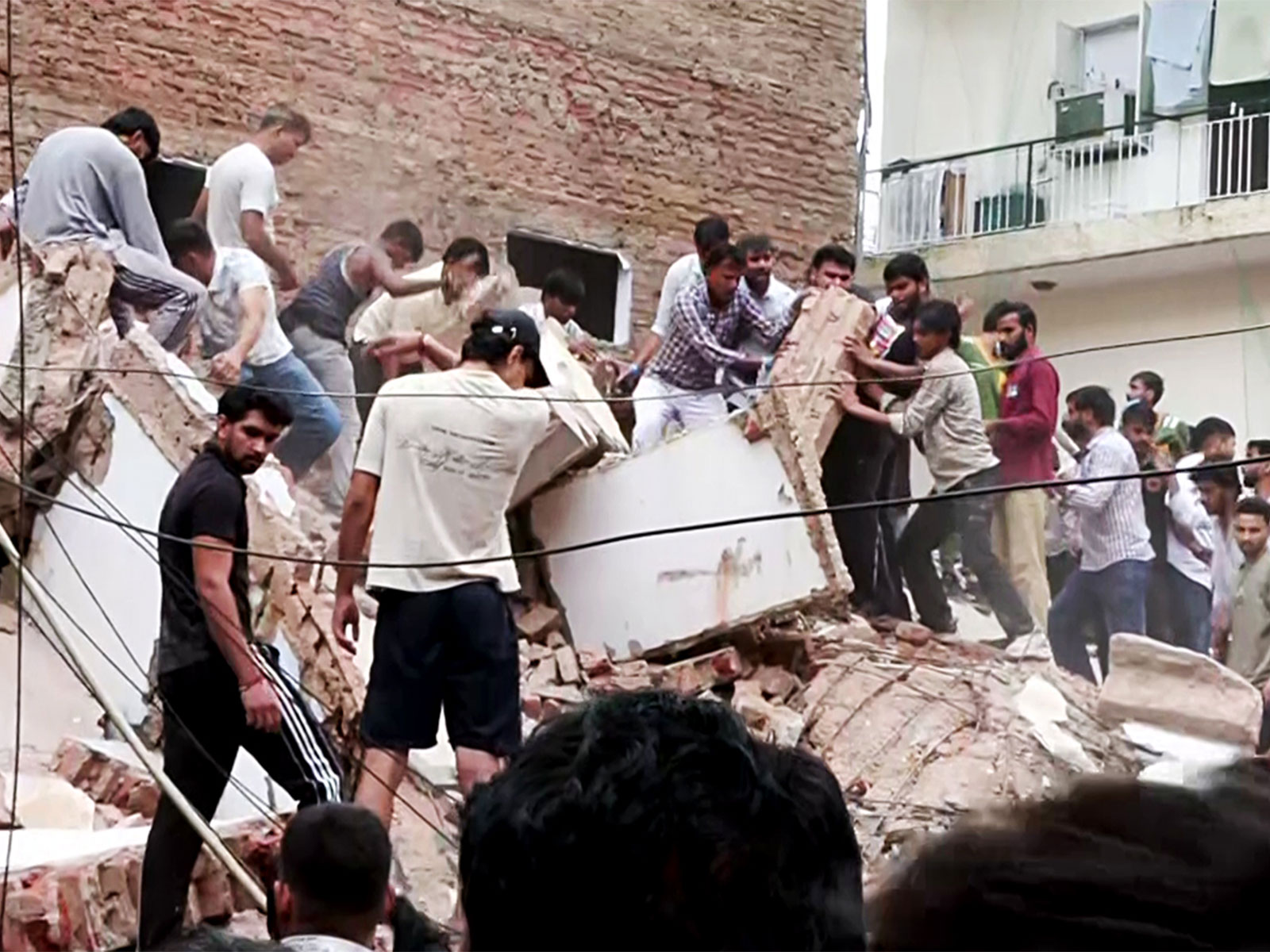 People remove debris during a rescue operation at the site of a building collapse near Satya Niketan in South-West Delhi (Photo/ANI) People remove debris during a rescue operation at the site of a building collapse near Satya Niketan in South-West Delhi (Photo/ANI)